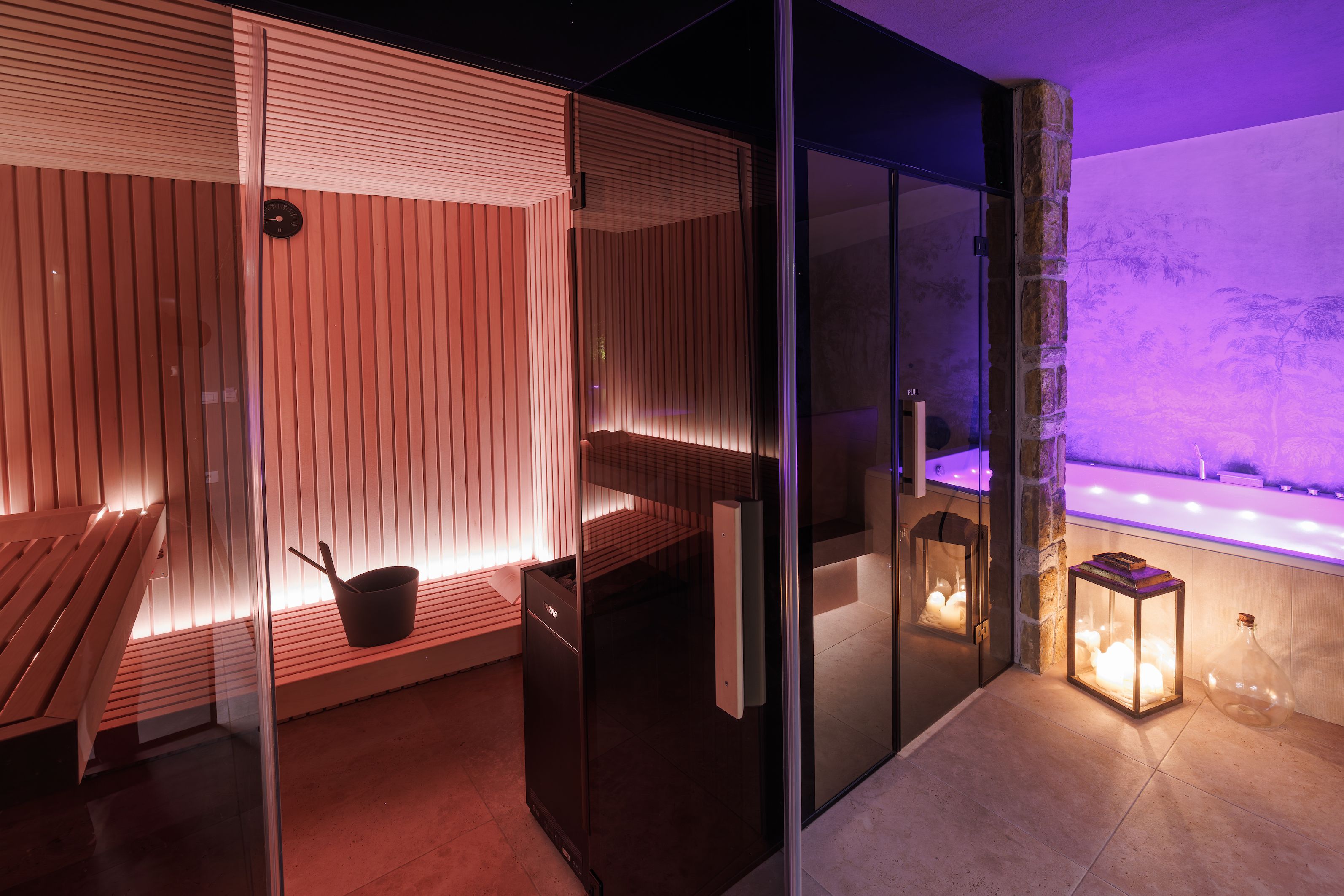 A modern spa area with a heated floor, a wooden bench, and a glass partition.