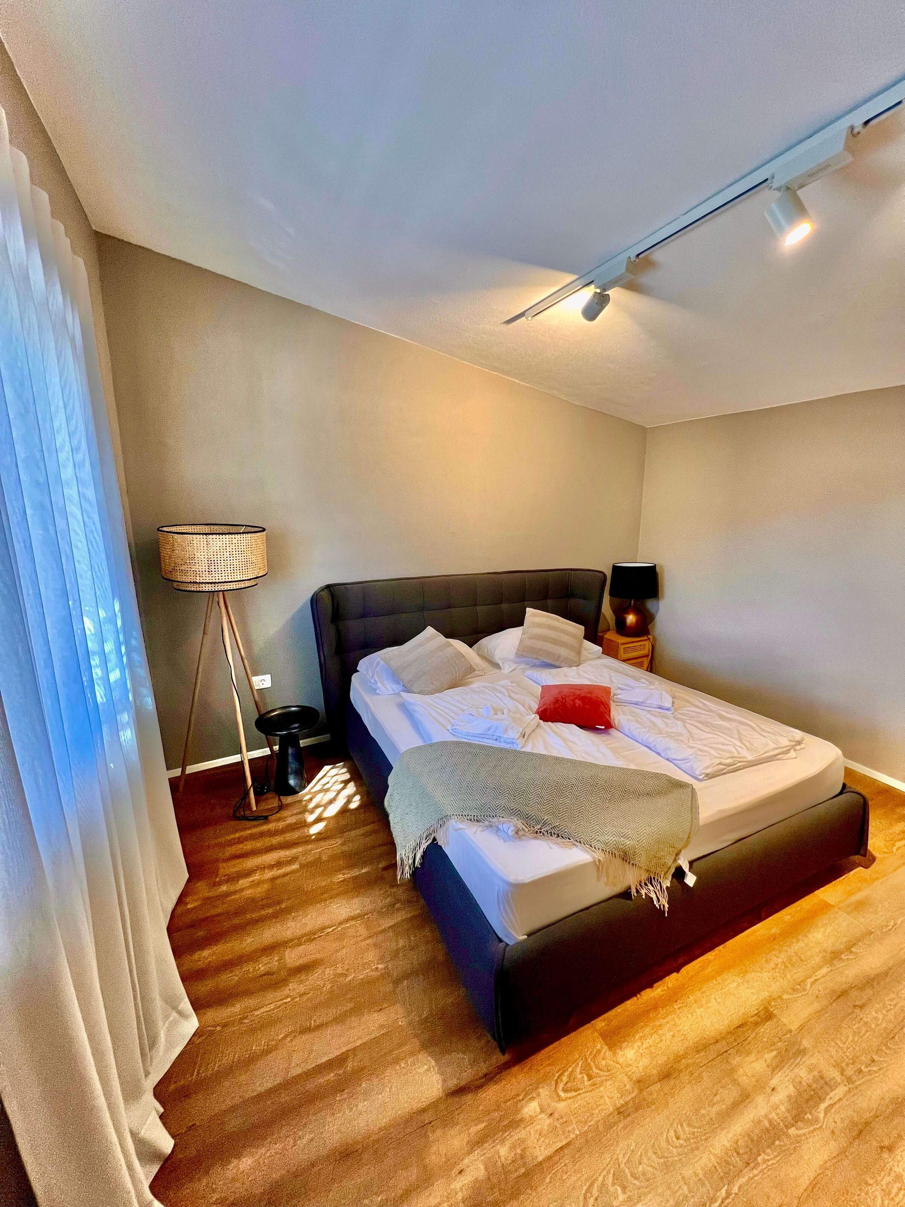 Een moderne slaapkamer met een groot bed, een bedlamp en een vloerlamp.