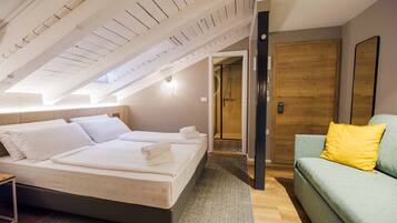 A bedroom with a bed, a wooden door, a green sofa, and a shower area.