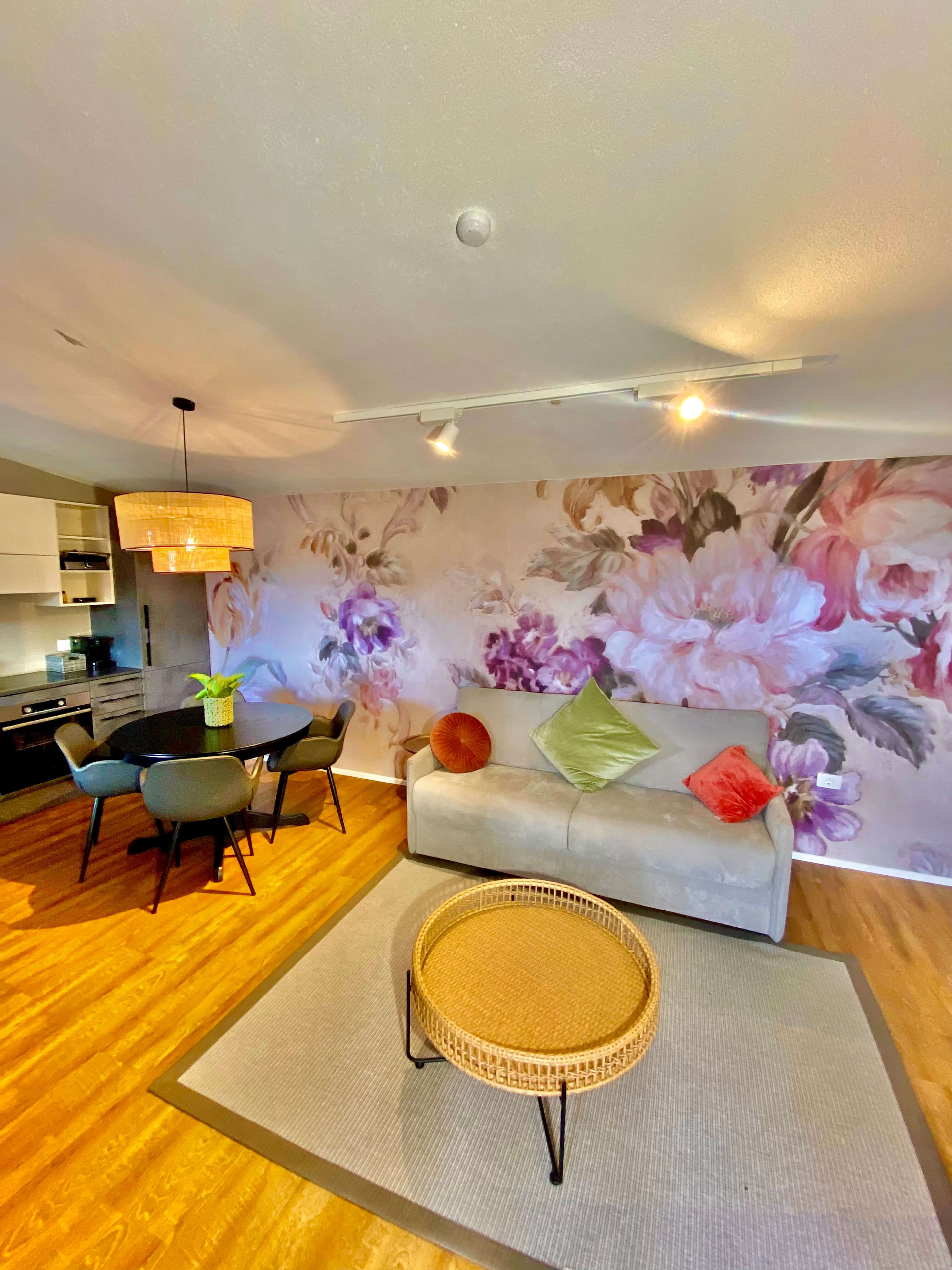Una sala moderna con un sofá, sillas, una mesa de comedor y una zona de cocina.