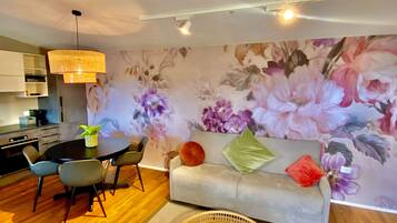 A modern living room with a sofa, chairs, a dining table, and a kitchen area.