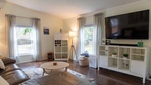 A living room with a leather sofa, a round coffee table, a TV on a stand, and a bookshelf. - 1-Bedroom Maltby Home: Perfect for Work & Leisure, Close to Wine Country (Snohomish)