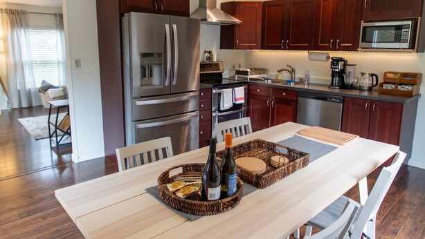 A modern kitchen with stainless steel appliances, wooden cabinets, and a dining area with a table set for two. - 1-Bedroom Maltby Home: Perfect for Work & Leisure, Close to Wine Country (Snohomish)