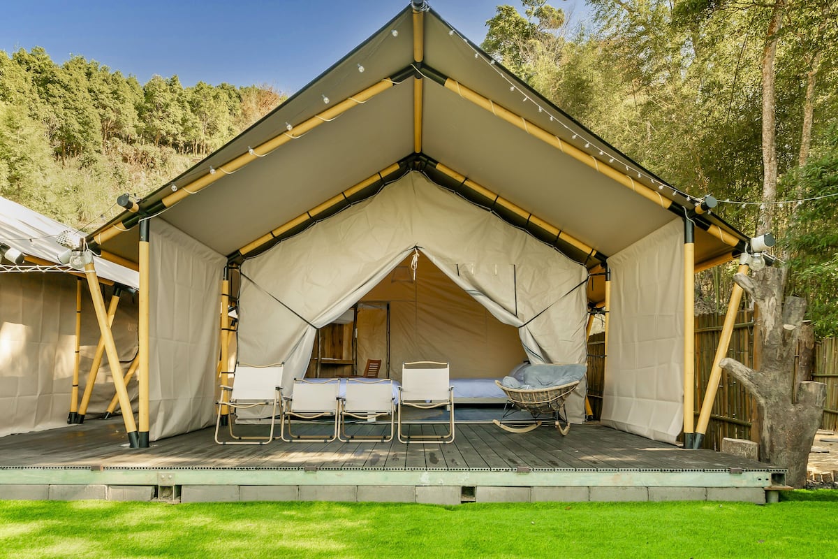 A tent with a flat roof, a wooden deck, and a small seating area with chairs and a table.