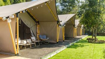 A row of tents with a wooden deck, chairs, and a hanging chair.