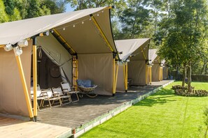 A row of tents with a wooden deck, chairs, and a hanging chair. - Grow Tree Glamping (Dahu)