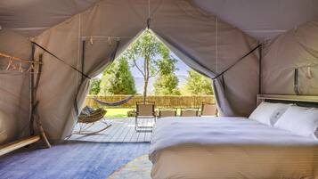 Alojamiento con tienda de campaña, cama, hamaca y vistas a árboles y montañas.
