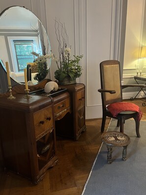 A wooden dresser with a mirror, a vase with white flowers, and a red cushion on a chair. - The Dery House  (Catasauqua)