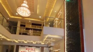 A hotel reception area with a reception desk, a chandelier, and a decorative wall. - Hotel Sahibs Red Carpet (Agra)