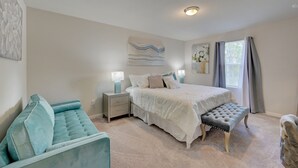 A bedroom with a bed, bedside tables, a bench, a sofa, and artwork on the walls. - Gulf Cost Home 5min to I-75 & Sunseekers Resort (Port Charlotte)