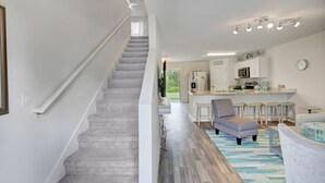 A modern interior with a staircase leading to a kitchen area, featuring a bar counter and seating. - Gulf Cost Home 5min to I-75 & Sunseekers Resort (Port Charlotte)