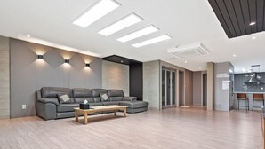 Una sala de estar moderna con sofá gris, mesa de centro de madera y luces empotradas en el techo.