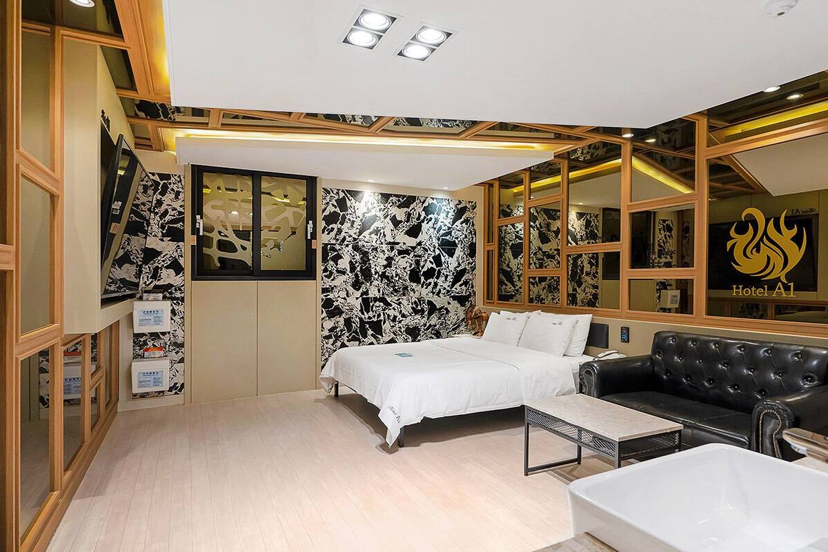Una habitación de hotel con cama, sofá, mesa y bañera.