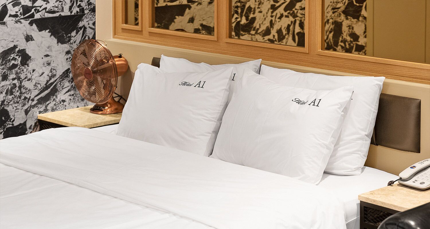 Una cama bien hecha con sábanas blancas y almohadas con la etiqueta "Hotel A1".