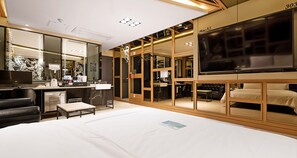 Une chambre d’hôtel dotée d’un grand lit, d’un bureau avec un ordinateur, d’une télévision et d’un coin salon avec un canapé et des fauteuils.