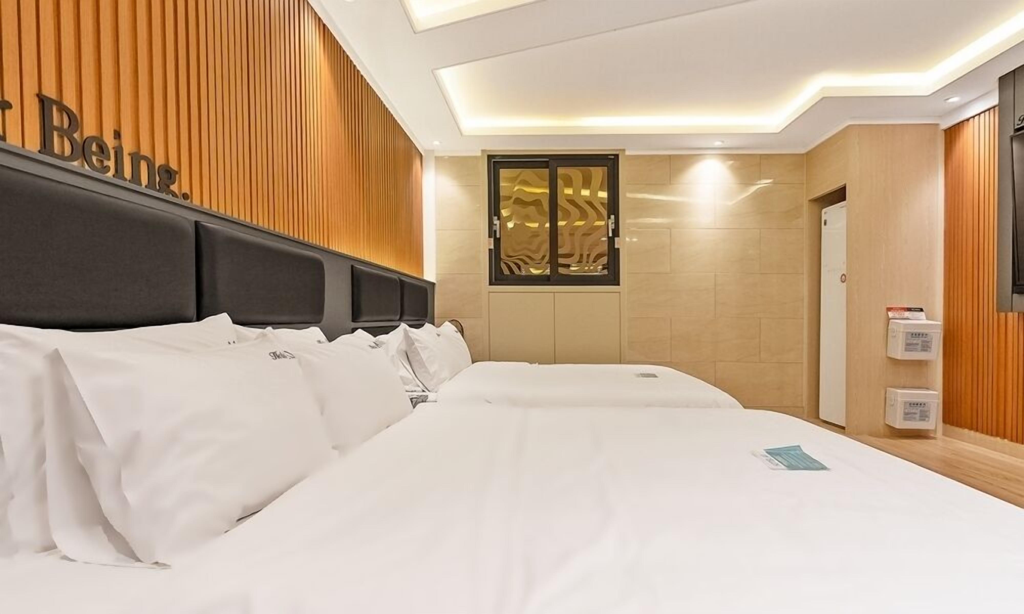 A hotel room with a large bed, wooden paneling on the walls, a window with a decorative view, and a sign that reads "Beina."