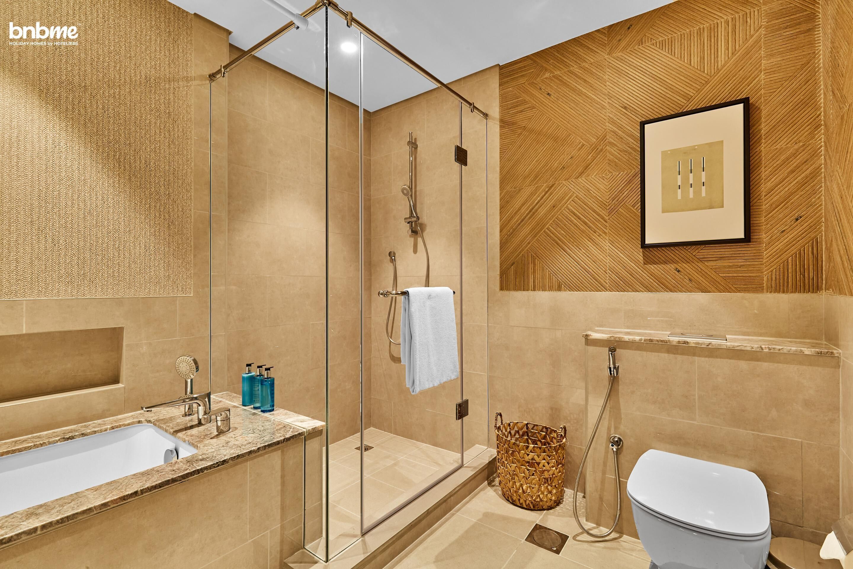 A modern bathroom with a glass-enclosed shower, a sink with a marble countertop, and a toilet.