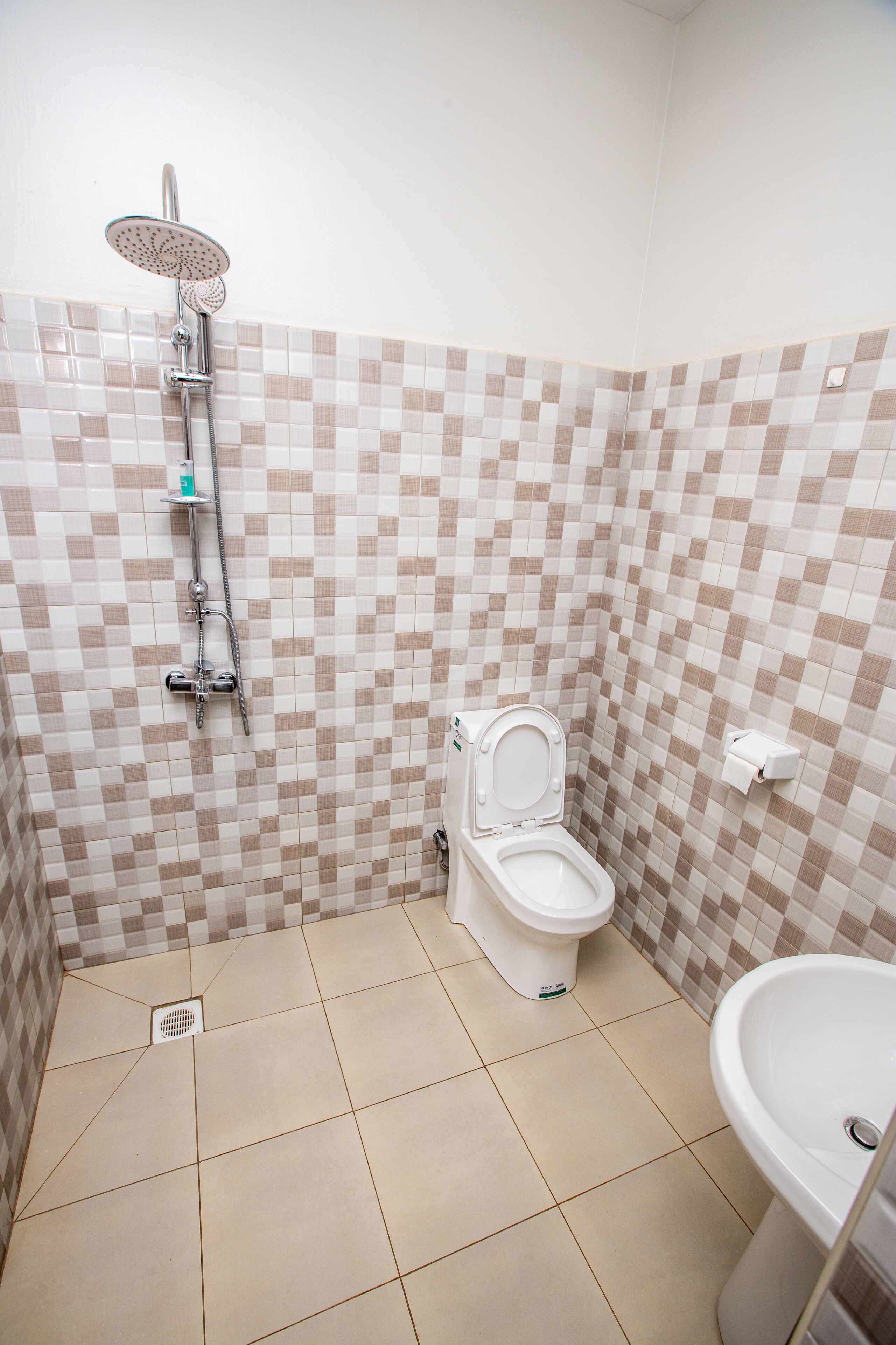 Et badeværelse med bruser, toilet og håndvask.