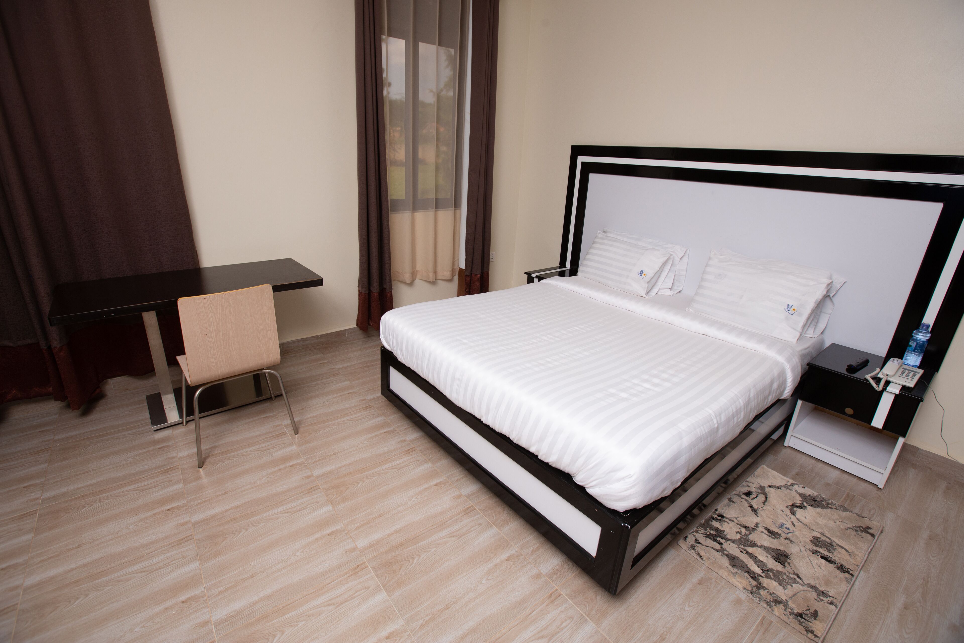 Habitación de hotel ordenada con una cama, un escritorio y una silla.
