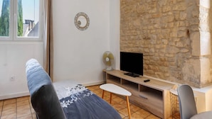 Una sala de estar moderna con pared de piedra, televisor de pantalla plana, ventilador y sofá.