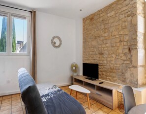 Un salon moderne avec un mur en pierre, un téléviseur à écran plat, un ventilateur et un canapé.