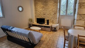 Una sala de estar con pared de piedra, televisor de pantalla plana, sofá, mesa de comedor y sillas.