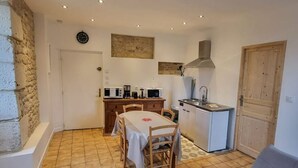 Cocina compacta con una mesa de comedor, sillas de madera, estufa integrada y un lavamanos pequeño.