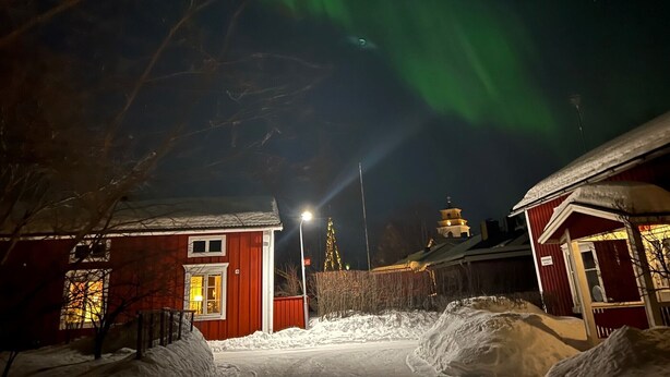 Un bâtiment rouge avec une fenêtre illuminée et un sol recouvert de neige.