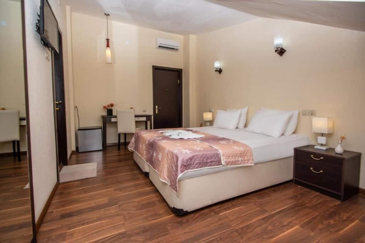 A bedroom with a bed, bedside tables, a desk, and a chair.