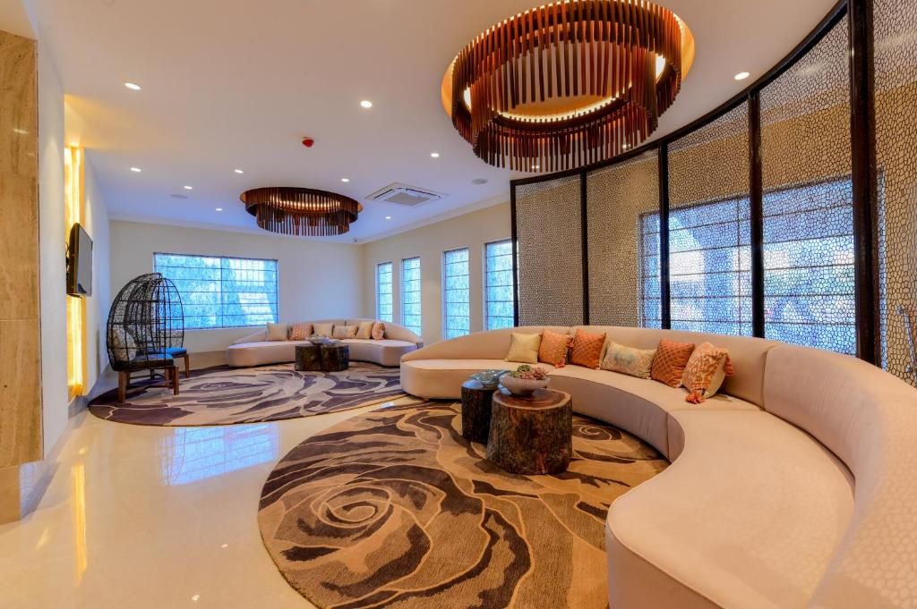A modern living room with a curved sofa, a patterned rug, and a unique ceiling light fixture.