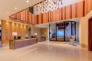 A hotel reception area with a modern design, featuring a reception desk, a seating area, and a glass partition. - Four A Resort Jammu (Samba)