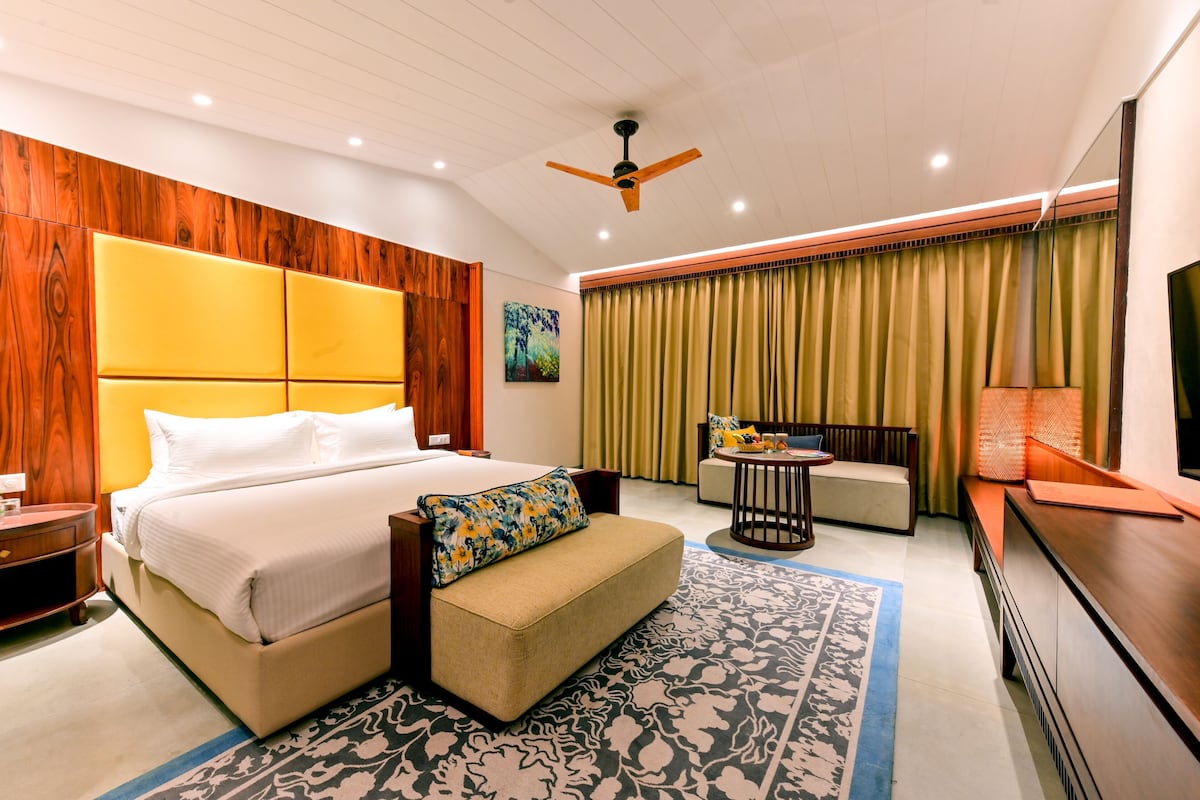 A hotel room with a large bed, a sofa, a small table, and a TV.