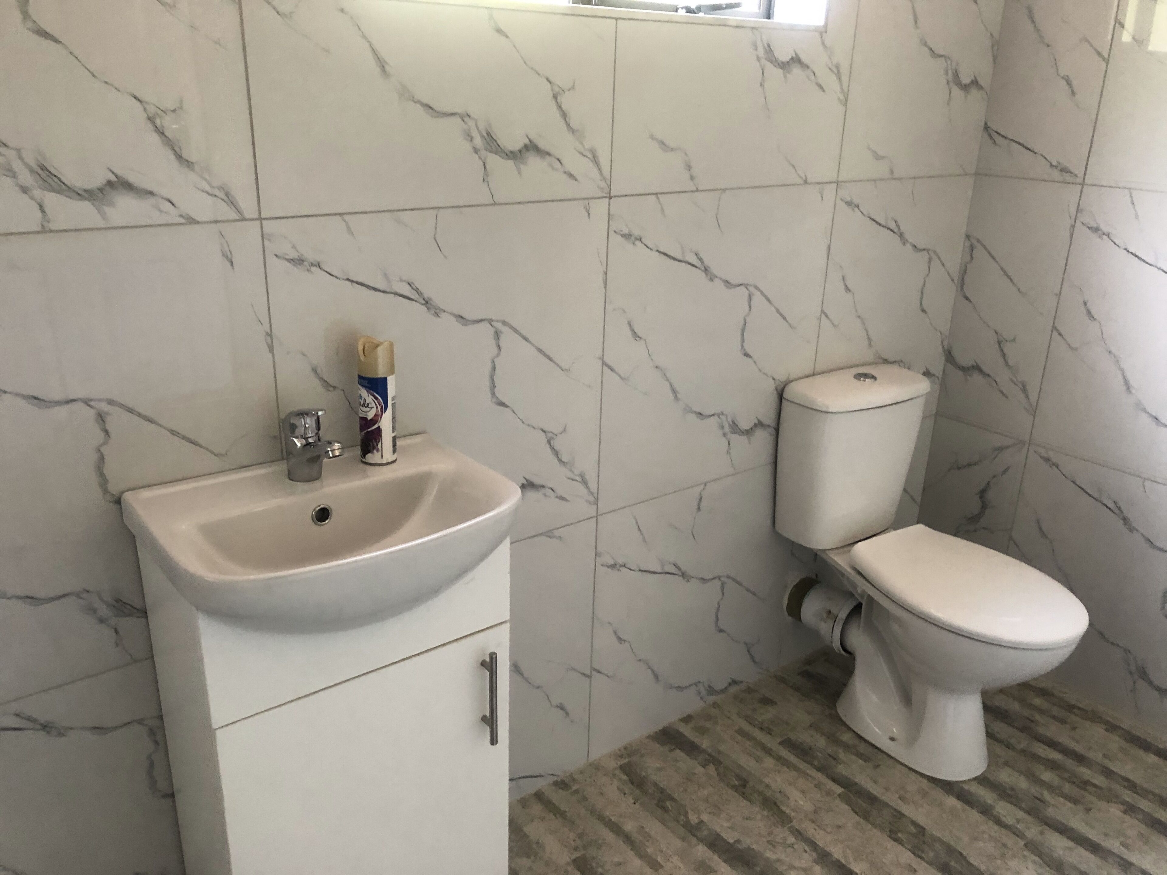 A bathroom with a white sink, toilet, and marble-patterned walls.