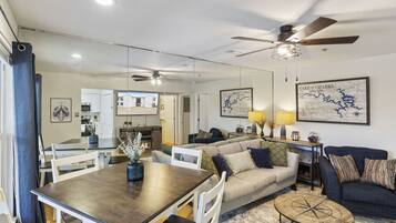 A modern living room with a dining area, a ceiling fan, and a large map on the wall.