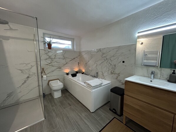 A modern bathroom with a bathtub, toilet, and sink.