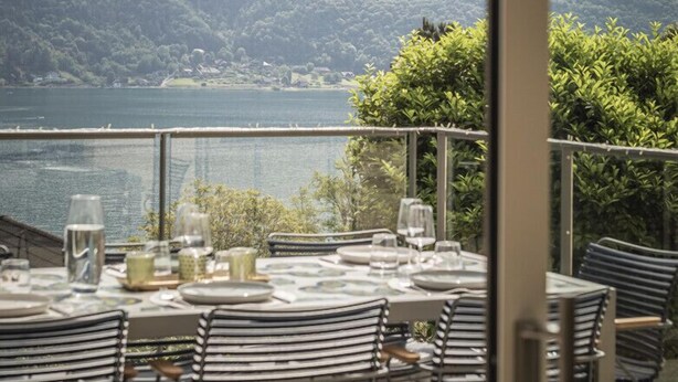 A dining area with a table set for four, overlooking a lake and mountains.