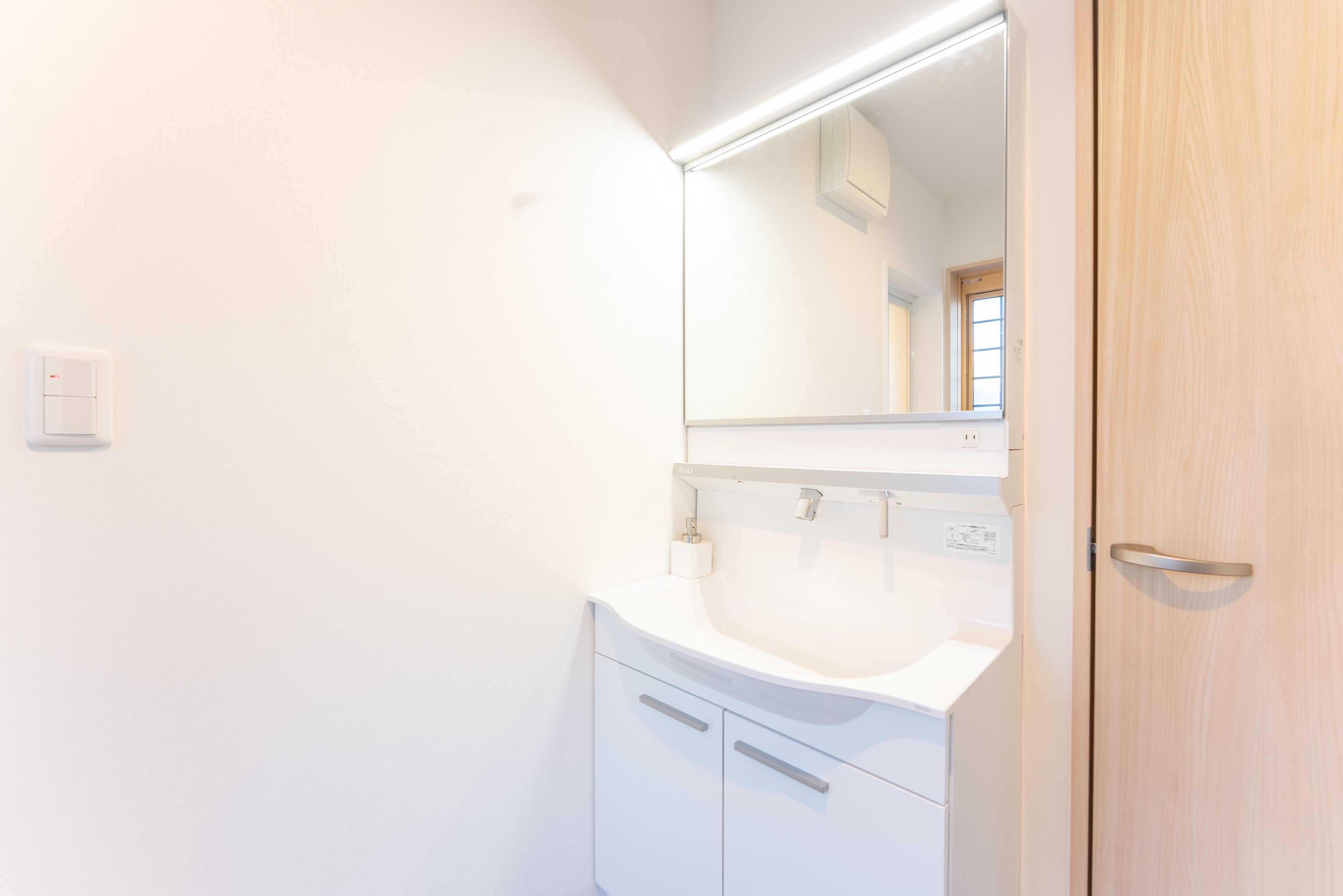 A bathroom with a white sink, a mirror, and a wooden door.