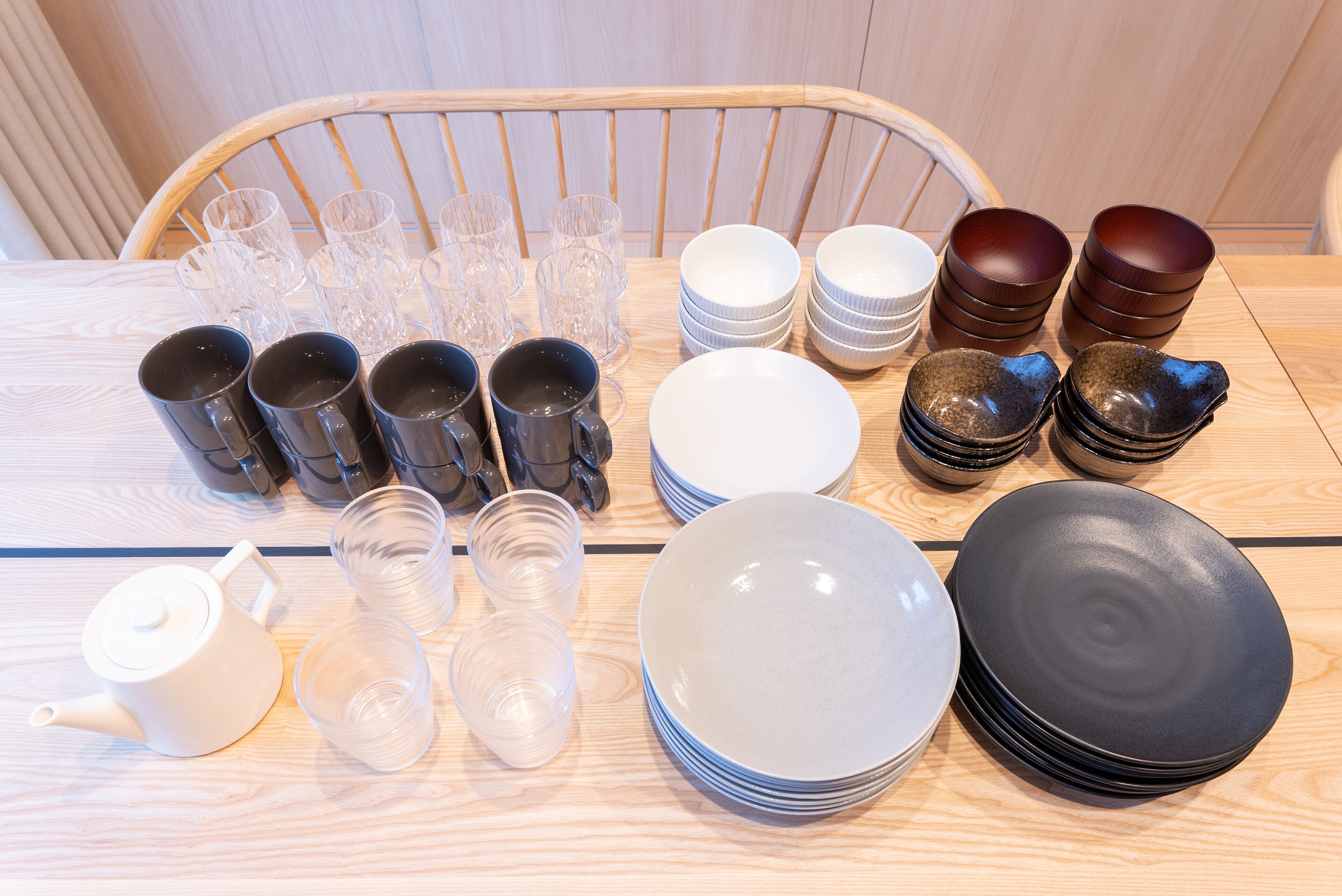 A table with various glassware, plates, and a teapot, arranged neatly.