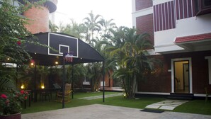 Un espacio al aire libre con un aro de baloncesto, un patio amueblado y un césped bien cuidado.