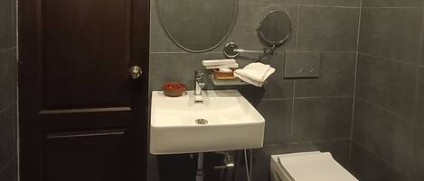 Un baño moderno con una puerta de madera oscura, un lavamanos blanco, un espejo y un inodoro.