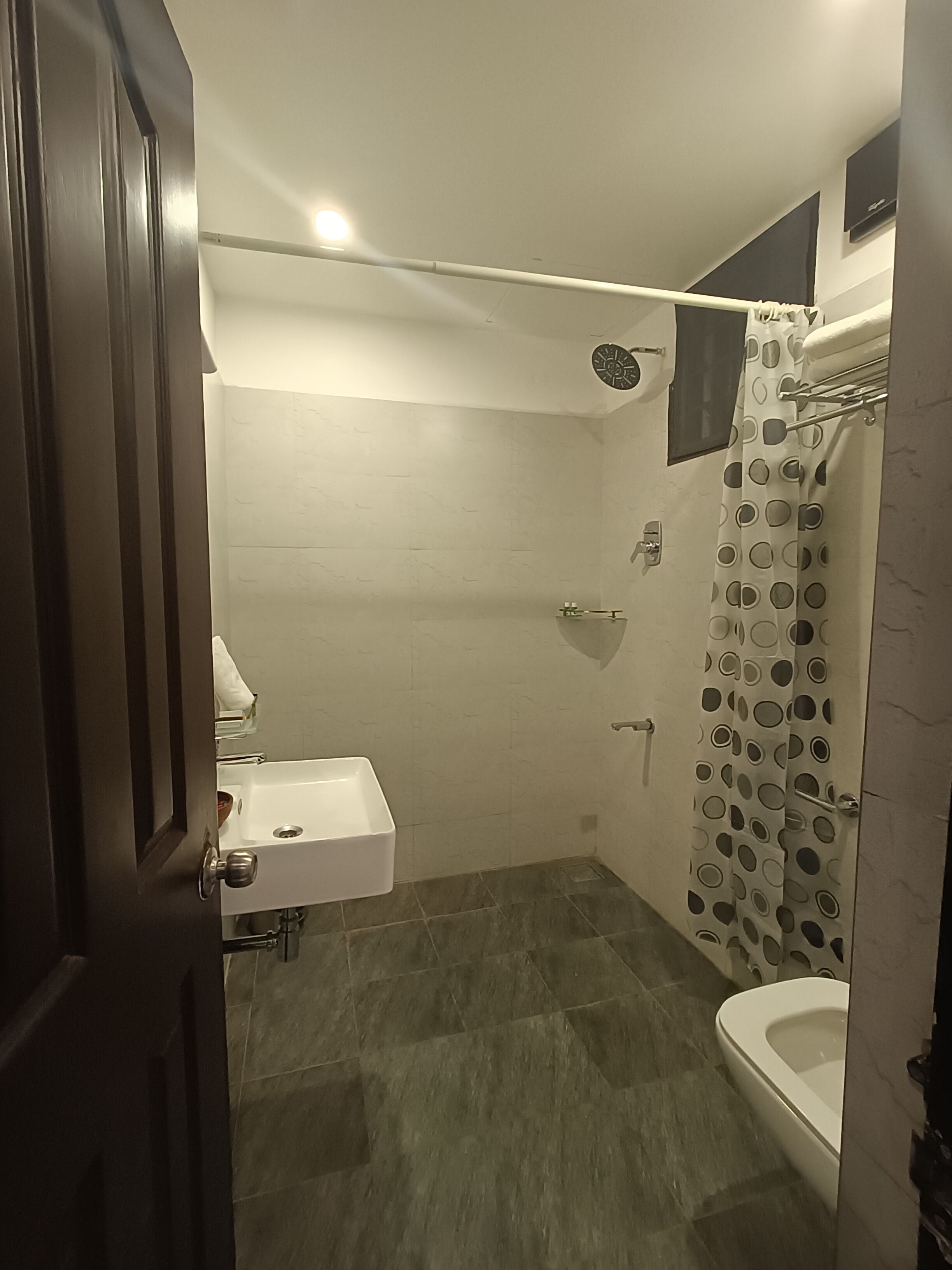 A small bathroom with a toilet, sink, and shower.