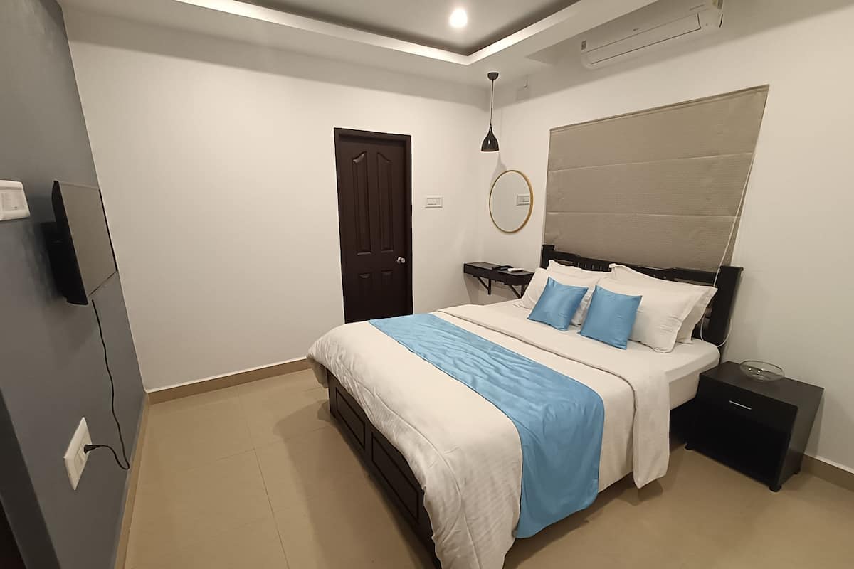 A modern bedroom with a bed, bedside tables, a nightstand, a mirror, and a door.