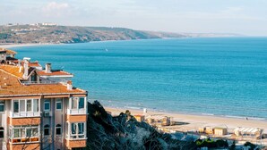 A coastal view with buildings overlooking the sea, a beach, and distant hills. - Miletus Otel (Sile)