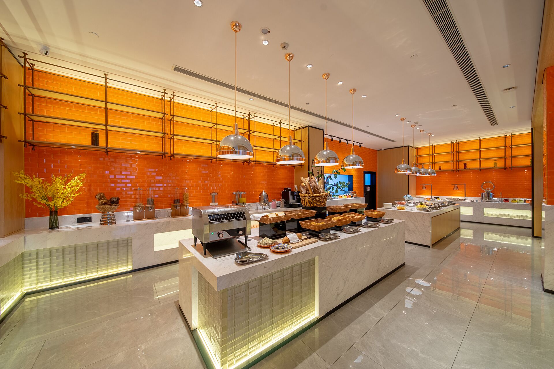 A modern kitchen with a central island, overhead lighting, and a brick wall backsplash.