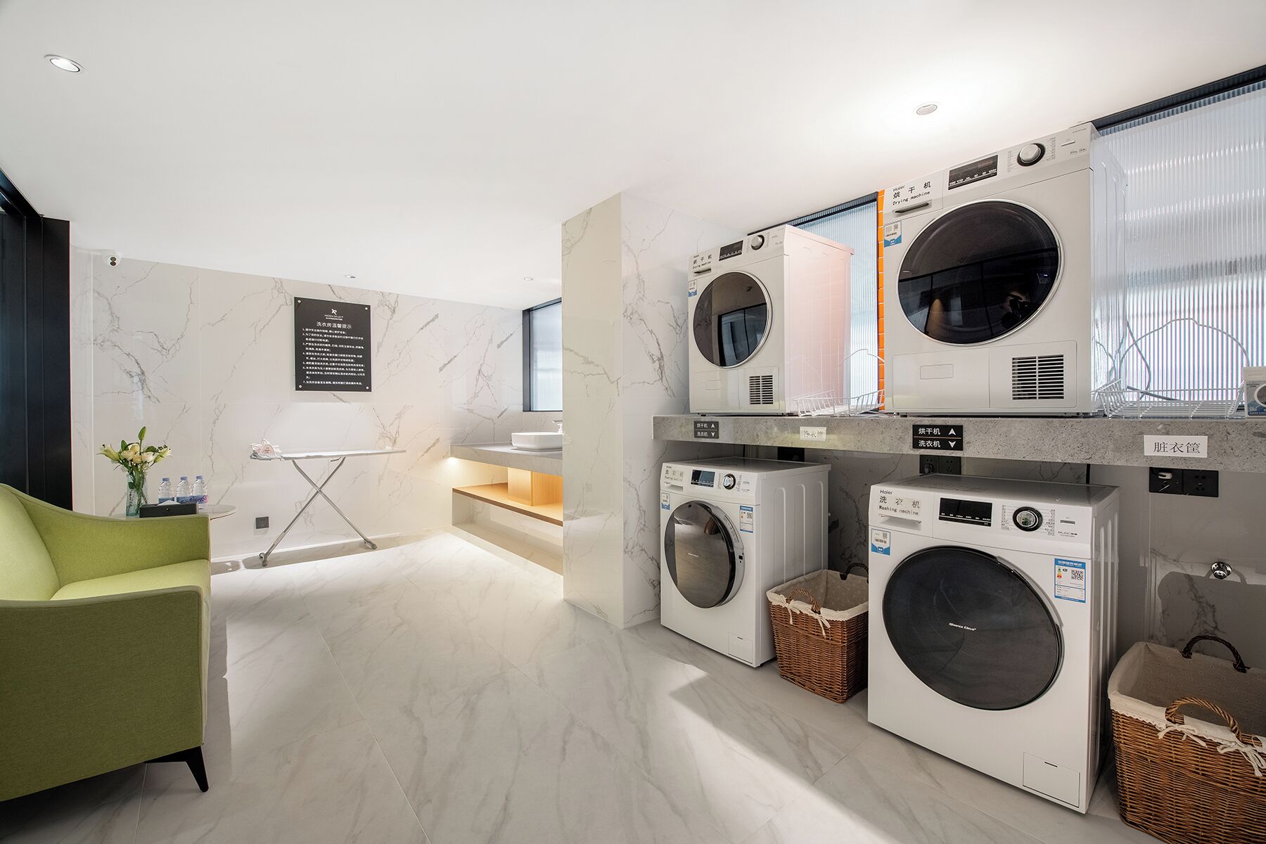 A modern laundry room with three washing machines, a sink, and a mirror.