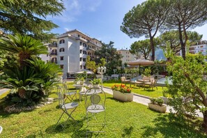 Une cour avec des espaces de détente en plein air, une piscine et un bâtiment doté de balcons.