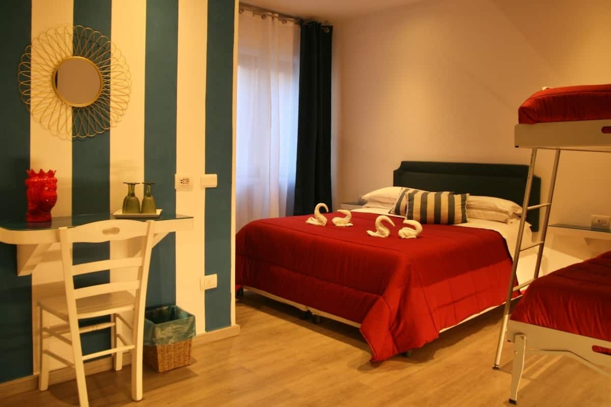 Een kamer met een stapelbed, een bureau met stoel, een spiegel en een raam met gordijnen.