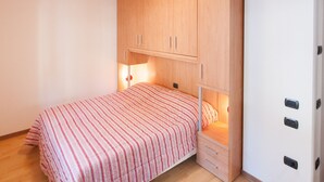 Een slaapkamer met een bed, een houten garderobe en een nachtkastje.