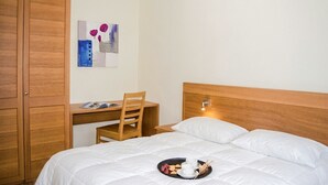 A hotel room with a bed, a desk, and a chair.