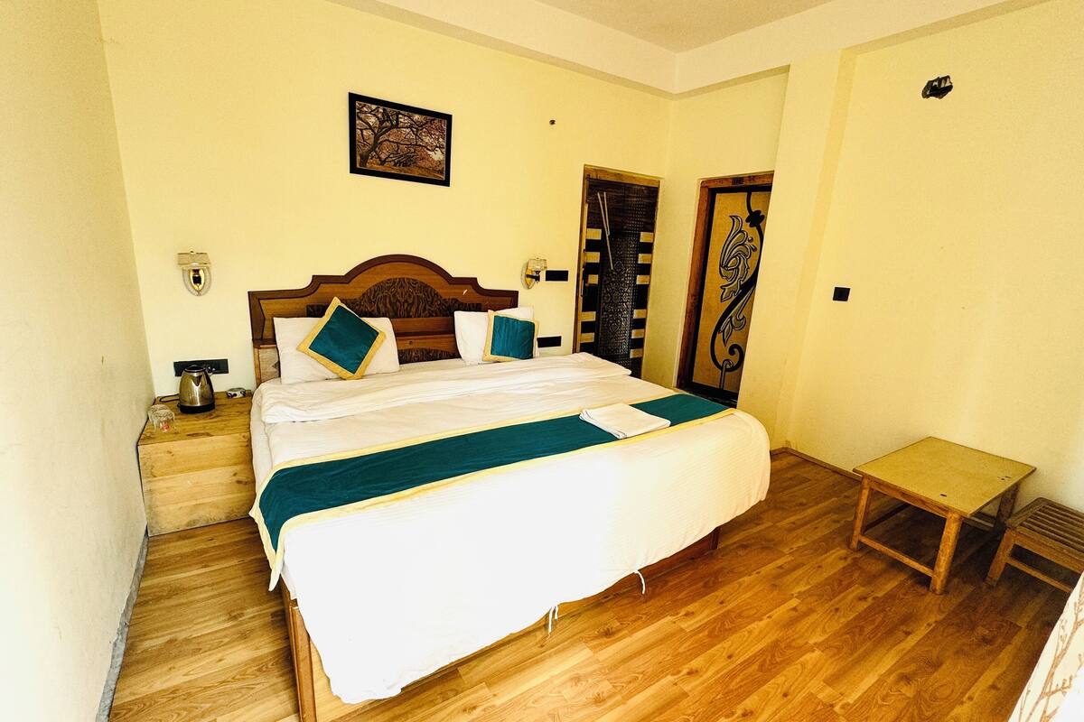 A neatly arranged bedroom with a wooden bed, a bedside table, a small table, and a door with a decorative panel.